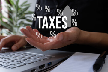 Concept of paying taxes. Businessman's hand holding the word taxis with several percentage signs around it and an upward arrow