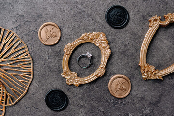 Engagement Ring with Wax Seals and Ornate Gold Frames on Stone Background