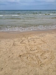 A hopscotch grid drawn in the sand awaits a player on the beach, a classic game inviting fun by the ocean.