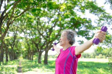 Happy Asian senior woman lifting dumbbell