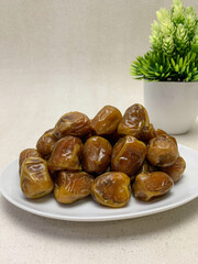 Sukkari dates (sukari dates). A decorative green plant is visible in the background.
