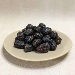 close up photo of a pile of Ajwa dates on a plate. ready to be served.