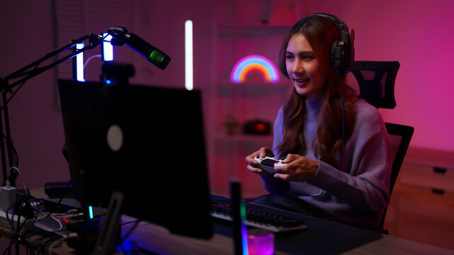 Asian woman gamer streaming playing video games controller home room neon setup