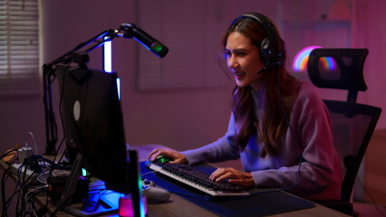 Young Asian woman gamer streamer playing online video game at home room setup