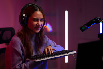 Asian woman gamer focused competitive online video game streaming dark room illuminated setup