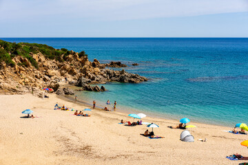 Tourists relaxing on the beach of Portu de S'Ilixi in Sardinia, Italy