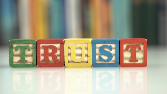 Wooden Blocks Spelling Trust in Vibrant Colors on a Reflective Surface with a Blurred Background of Books Representing Education and Support