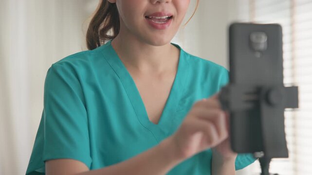 Young adult woman Gen Z asia people anti aging expert modern nurse live talk viral video selfie camera on mobile phone app mental health care. Online sharing digital virtual asian vlogger filming.