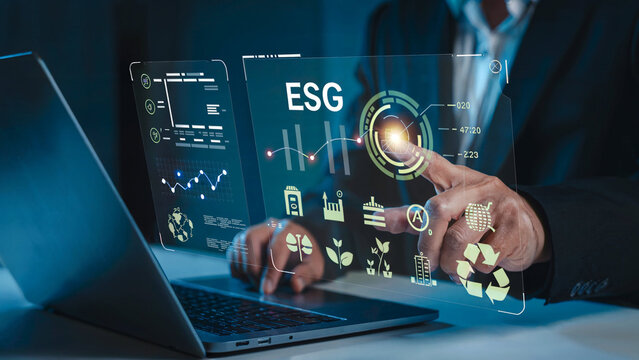 Businessman interacting with a futuristic digital interface displaying esg metrics and sustainability data on a transparent screen - Powered by Adobe