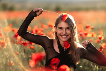 Poppy Flowers Model: Woman smiles playfully, wearing poppy on head in poppy field during golden...