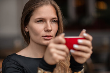 Woman Coffee Cafe: Girl holds red cup, likely coffee, at a cafe possibly for a morning drink.