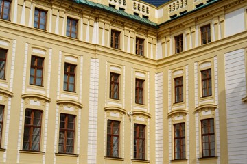Discover the architectural beauty of a historic building in Prague. This facade features ornate windows and vibrant yellow walls, showcasing the city s rich design heritage.