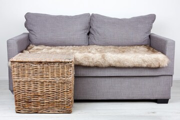 Gray couch with faux fur throw and wicker side table