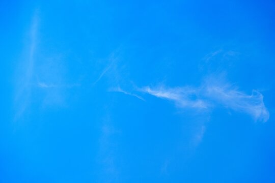 A stunning view of a bright blue sky with soft, wispy clouds. This serene image conveys tranquility and openness, making it perfect for backgrounds or creative projects.