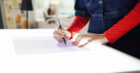 Woman, hands and drawing with light table for fashion design, art or tracing in home studio. Female...