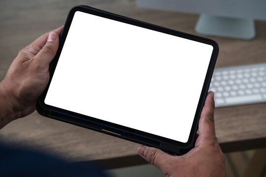 A businessman holds a mockup. iPad digital tablet with blank screen Mockup replaces your design mockup in the office. - Powered by Adobe