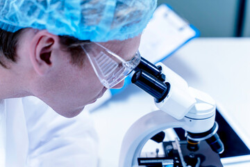 Closeup scientist looking in microscope while working on medical research in science laboratory