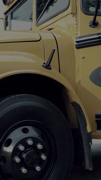 Heavy-duty truck detail. Chrome accents gleam against a yellow body and rugged tire. A look at power and functionality