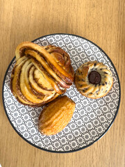 Assorted French Pastries with Cinnamon Roll, madeleine and Mini Cake on Patterned Plate