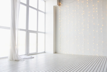 Bright minimalist room with large window and soft hanging string lights creating a serene atmosphere.