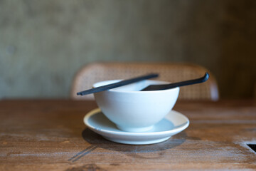 A set of tableware on a restaurant table, white bowls, black chopsticks and black spoon