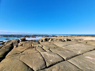 Eroded wave cut rock platform with exposed joint lines. Near the ocean under a blue sky. Soldiers Point New South Wales Australia