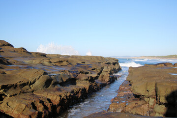 Ocean waves crashing over an eroded rock platform and boulders at Soldiers Point New South Wales Australia. 