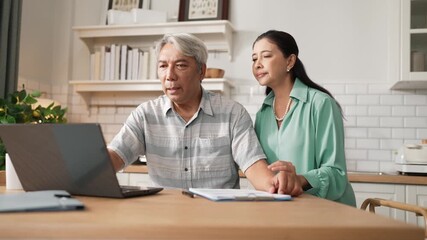 Grandmother comforting and encouraging senior smart manager working and pointing at laptop showing deceasing financial chart. Elder couple helping and talking together while sitting at home. Myrmidon. - Powered by Adobe
