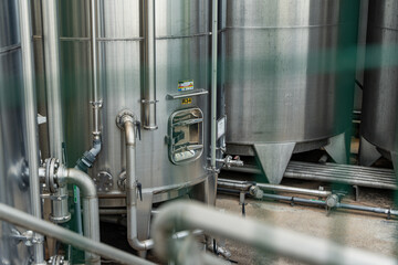 Gros plan de grandes cuves en inox photographiées en extérieur, illustrant leur surface métallique brillante et leur usage industriel.