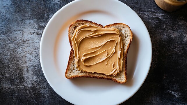 Slice of Bread with Peanut Butter Spread on a White Plate