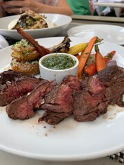 Sizzling steak perfection! Juicy slices of medium-rare goodness, served with roasted veggies, potatoes, and homemade chimichurri.