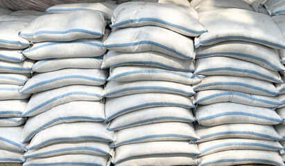 A pile of white sacks filled with soil and gravels stacked on one another. Sacks are used to store...