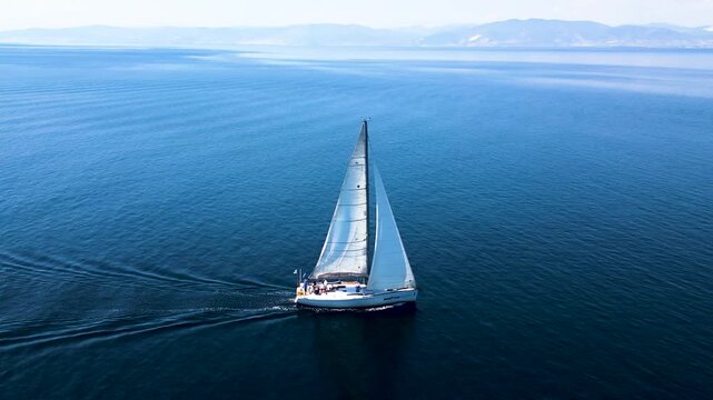 A sailboat sails the sea around the island of Thassos video footage taken by a drone