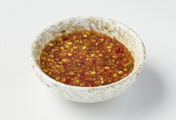Bowl of spicy chili dipping sauce with visible chili seeds, served in white ceramic bowl with speckled design, perfect for enhancing flavor of various dishes