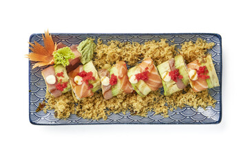 Beautifully arranged sushi platter featuring salmon, avocado, and rice, garnished with red roe, mayonnaise, and crispy tempura flakes, served on decorative blue plate with leaf garnish