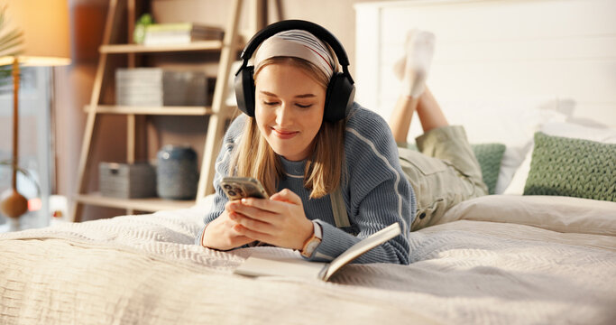 Happy, bed and woman with headphones and notebook for relaxing, writing in journal and social media. Bedroom, chill and person with phone listening to audio, radio and streaming music for inspiration