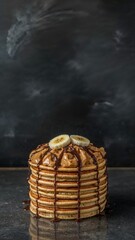 Tall stack of pancakes with peanut butter, bananas, and drizzle on dark background