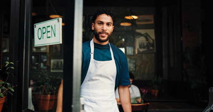 Happy man, portrait or open sign with door in cafe for small business startup or welcome. Male person, waiter or owner with smile by entrance, storefront or ready for catering service in coffee shop