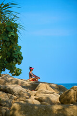 a woman meditates on the rocks by the sea