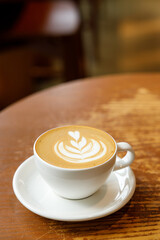 Cup of hot milk latte coffee on table by the window.