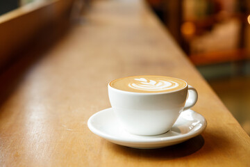 Cup of hot milk latte coffee on table by the window.