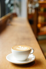 Cup of hot milk latte coffee on table by the window.