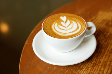 Cup of hot milk latte coffee on table by the window.