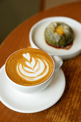 Cup of hot milk latte coffee on table by the window.