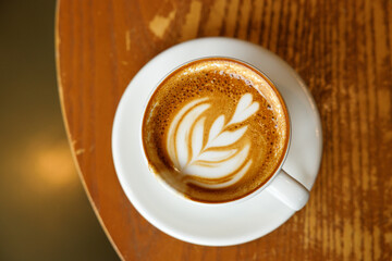 Cup of hot milk latte coffee on table by the window.