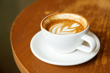 Cup of hot milk latte coffee on table by the window.
