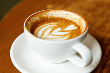 Cup of hot milk latte coffee on table by the window.