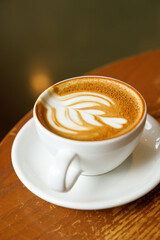 Cup of hot milk latte coffee on table by the window.