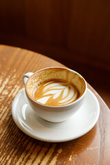 Cup of hot milk latte coffee on table by the window.