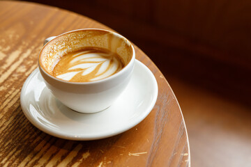 Cup of hot milk latte coffee on table by the window.